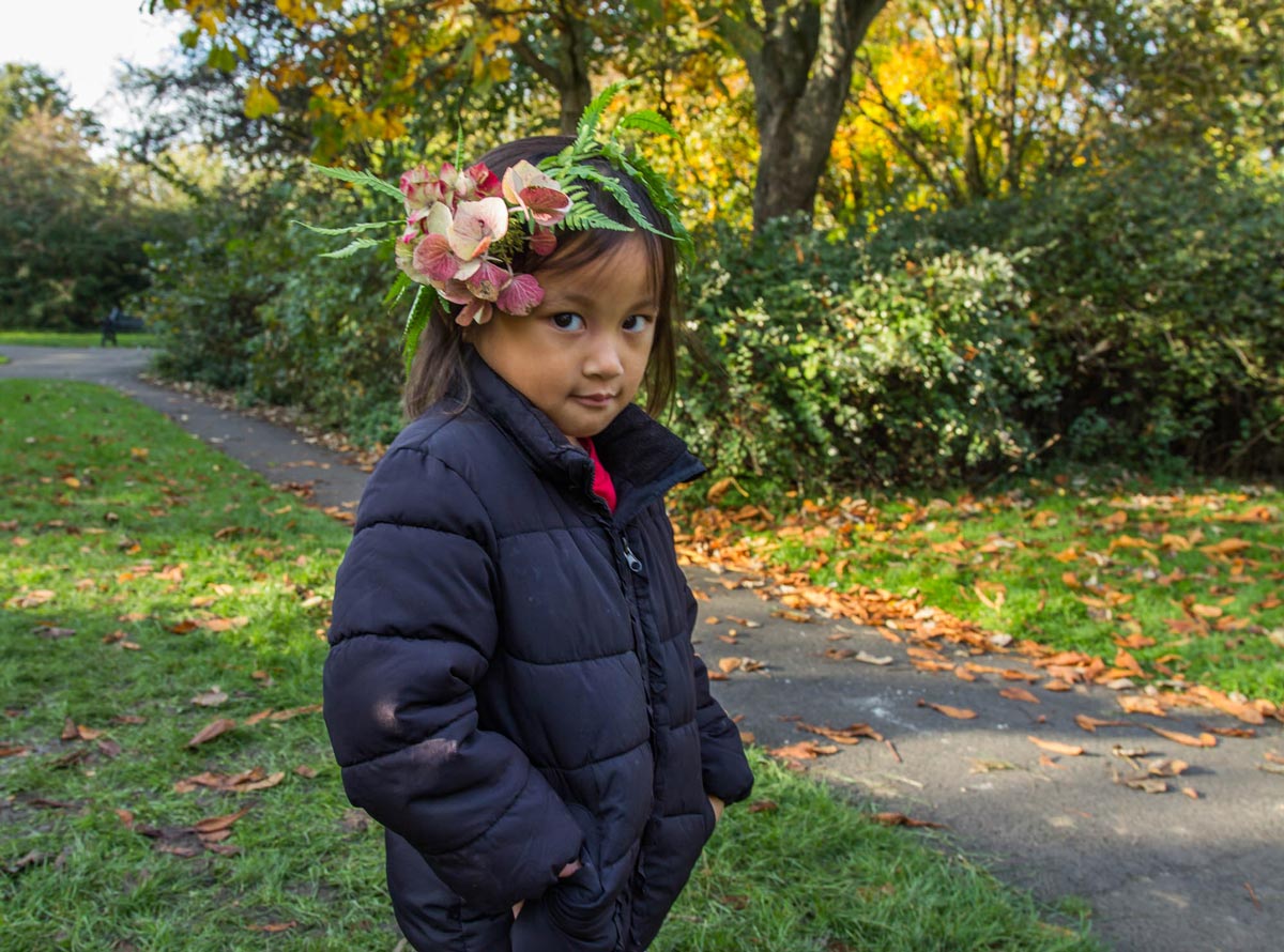 A shy girl wearing a garland poses to the camera.