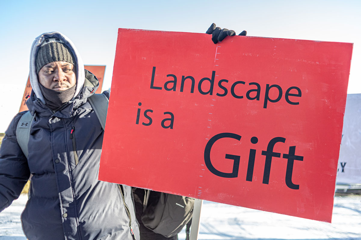 A man looking at a banner that reads: Landscape is a Gift.
