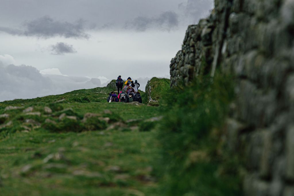 A group of people walking in a distance by Hadrian’s Wall.